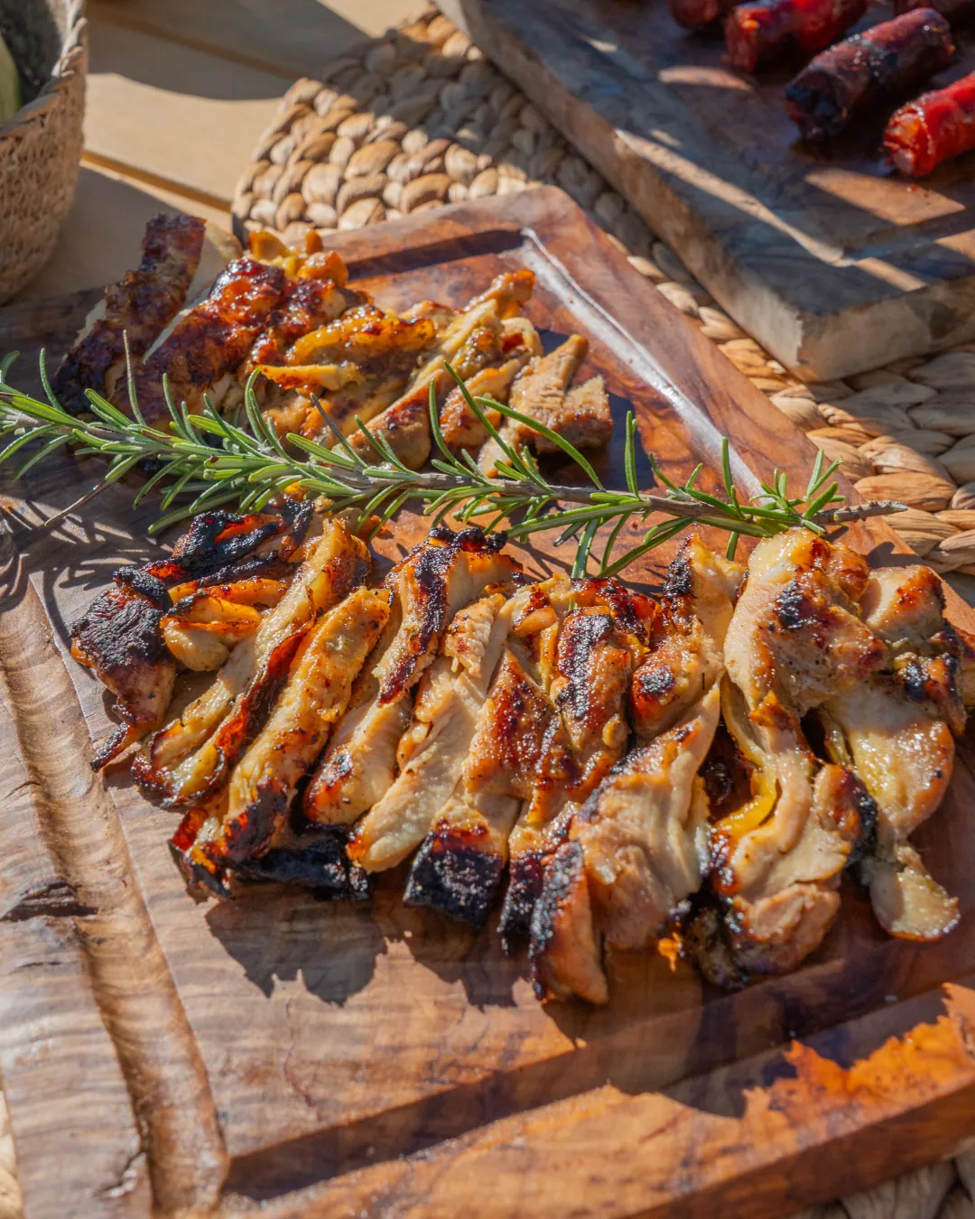 Composición de mesa de gala exterior enfocando una copa de vino tinto alzada en primer plano y un chuletón trinchado al fondo