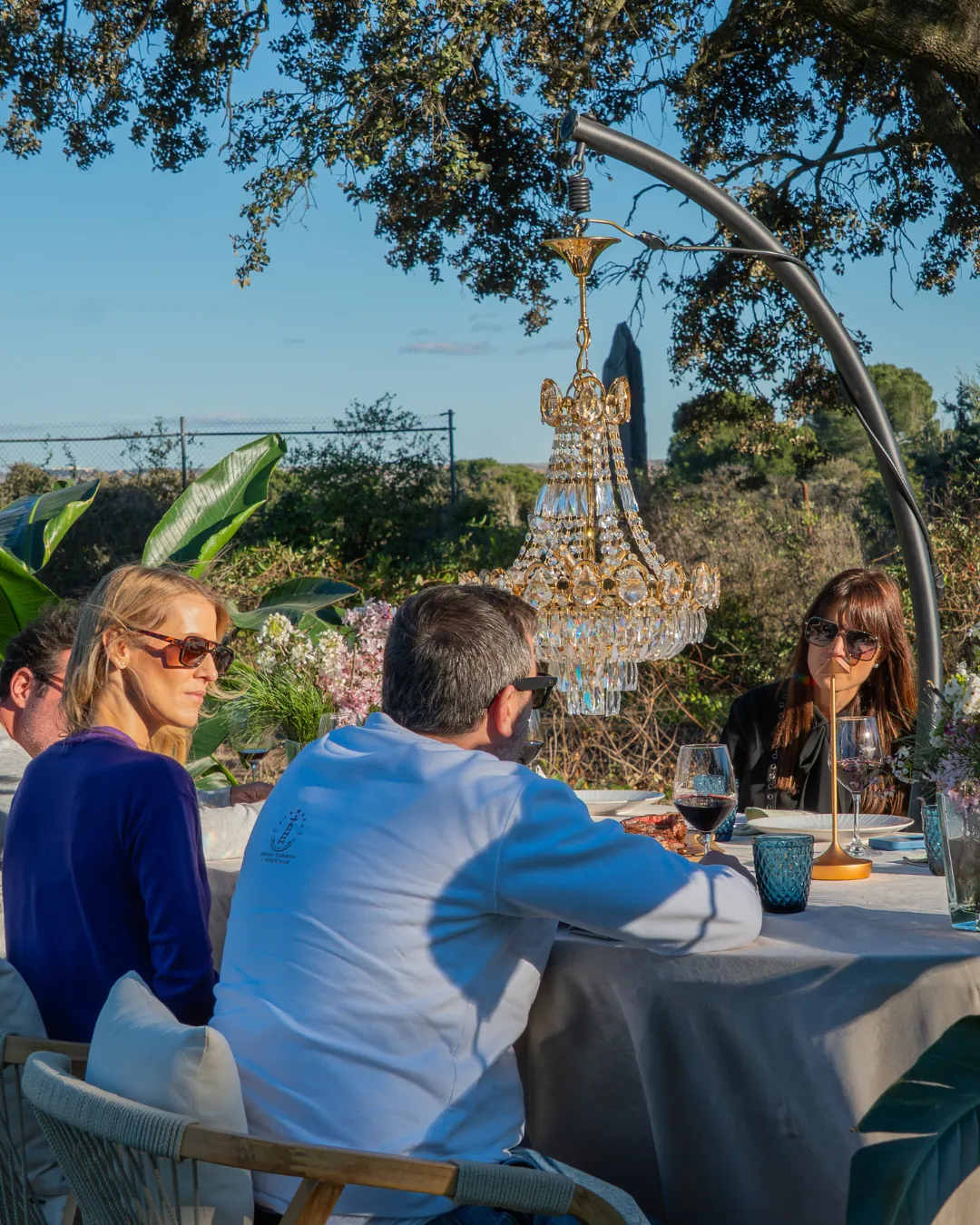 Plano general de la mesa de gala con todos los comensales y la iluminación ambiental del atardecer