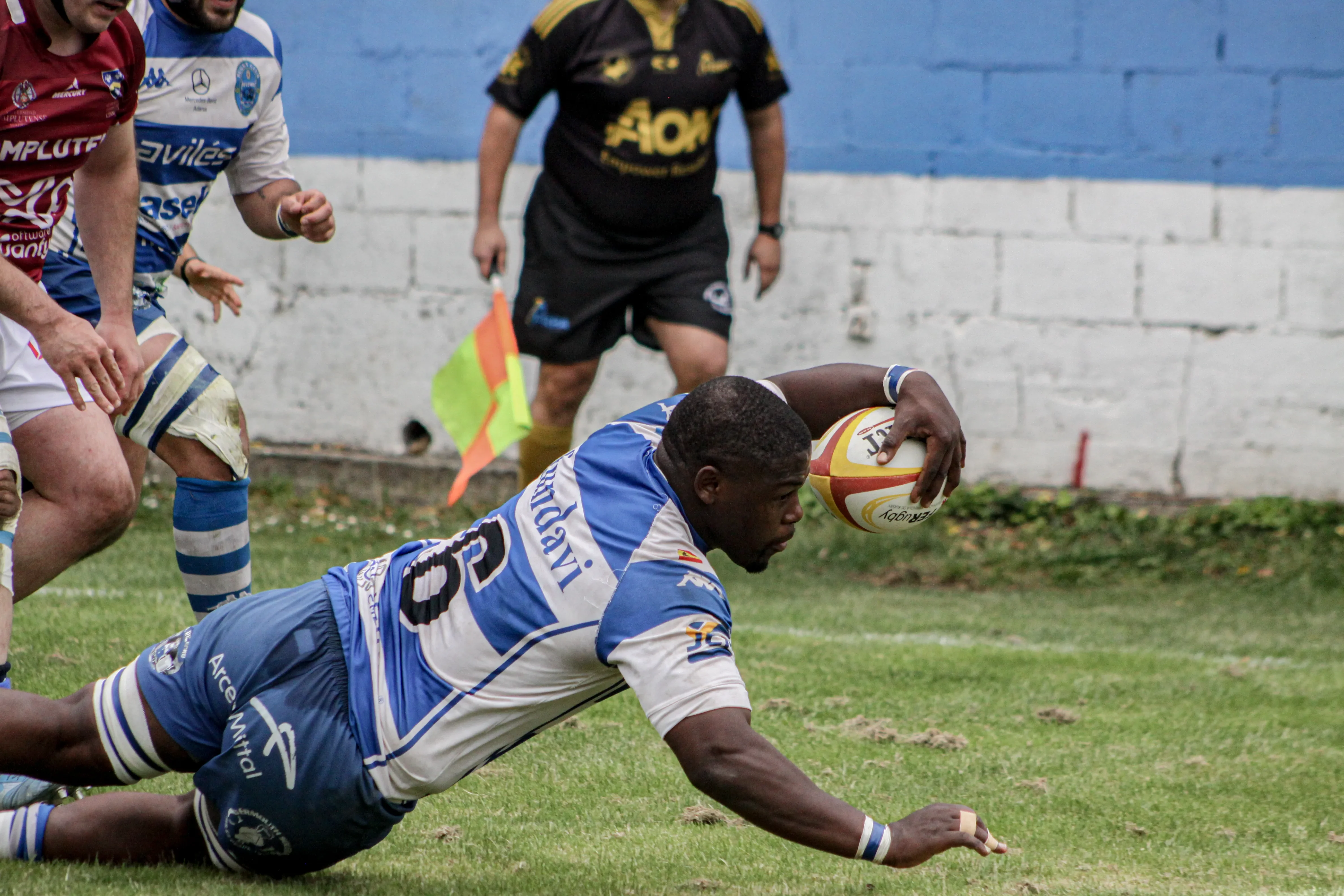 Jugador de rugby apoyando el balón para conseguir un ensayo durante un partido oficial.