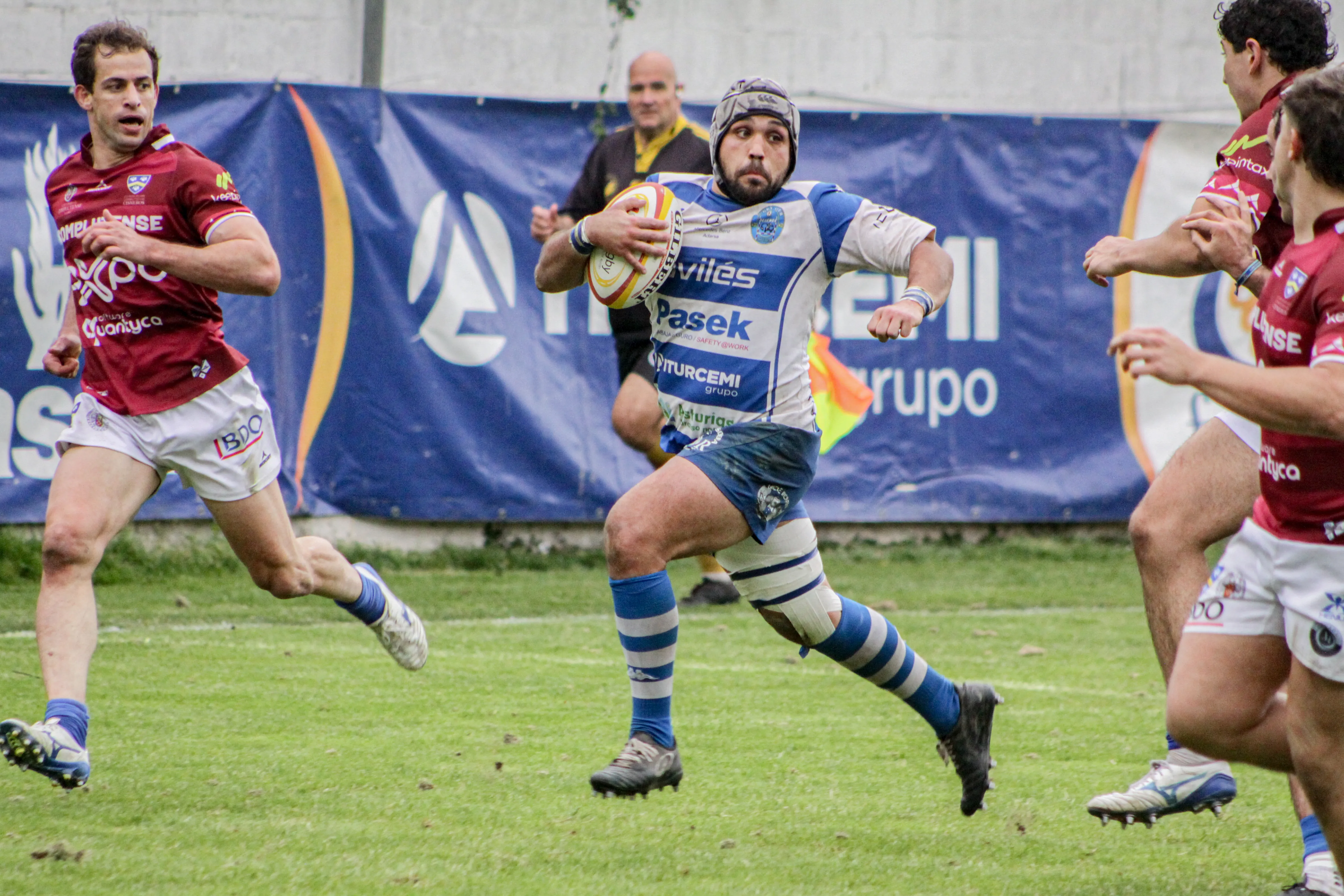 Jugador avanzando con el balón durante una jugada ofensiva en un encuentro de rugby.