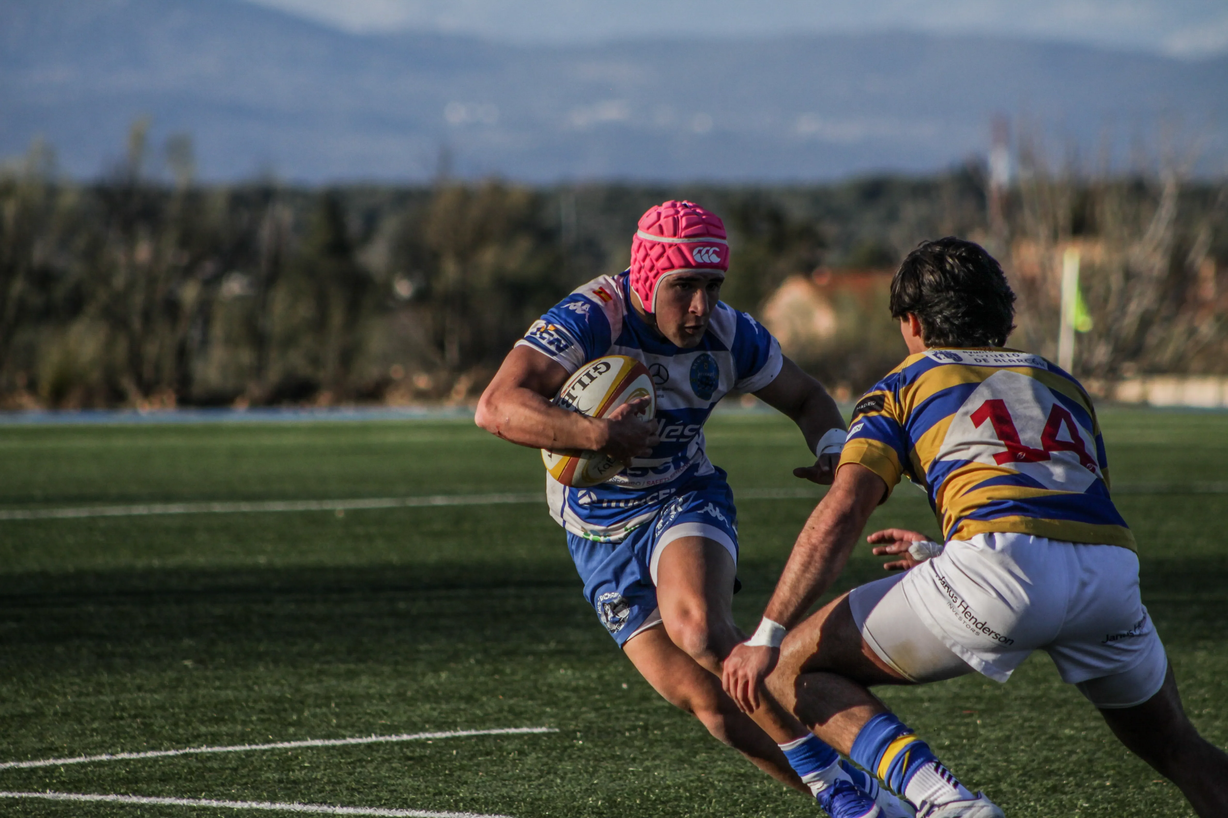 Carrera con balón durante un encuentro de rugby bajo la presión de la defensa.