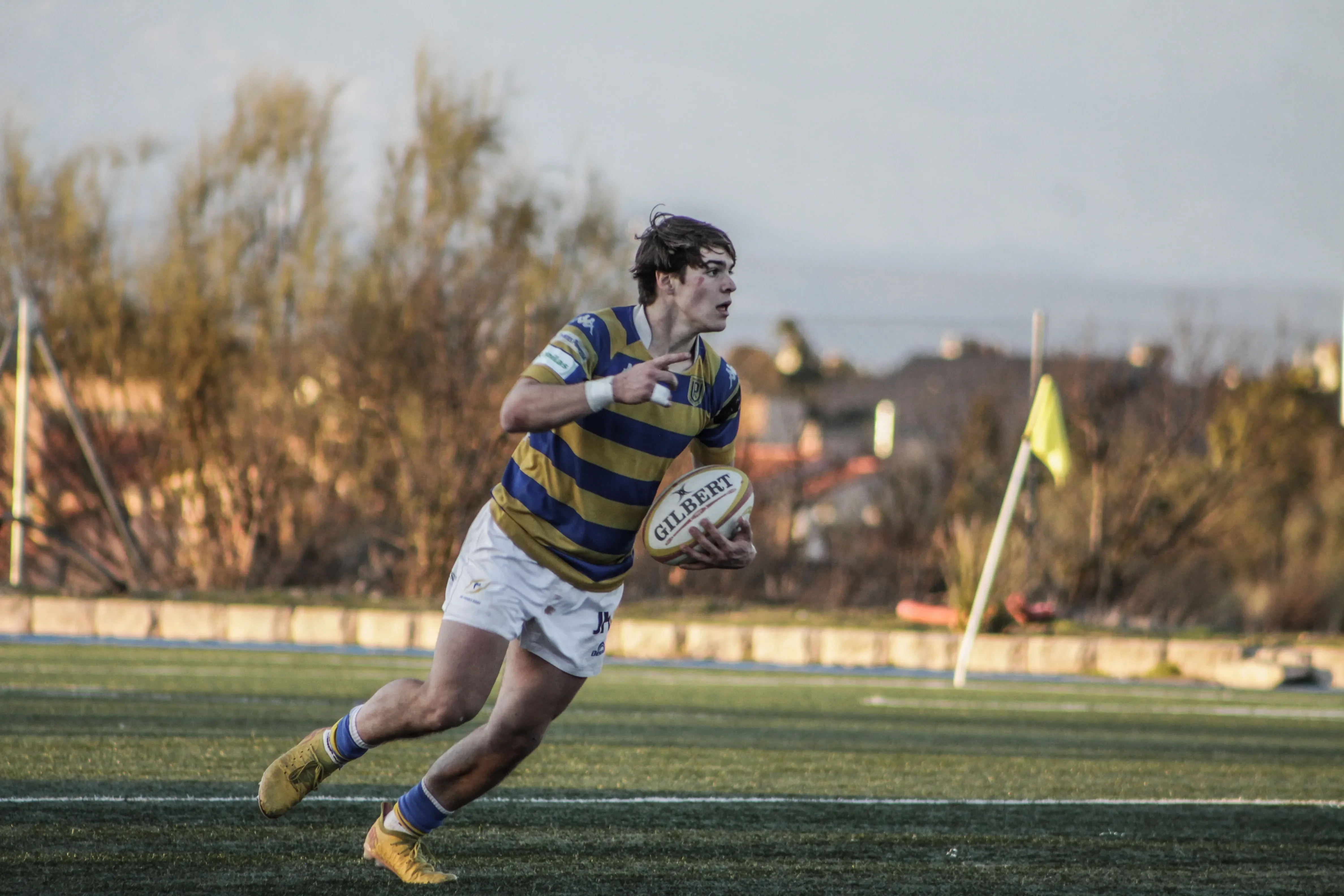 Jugador corriendo con el balón durante una acción ofensiva en un partido de rugby.