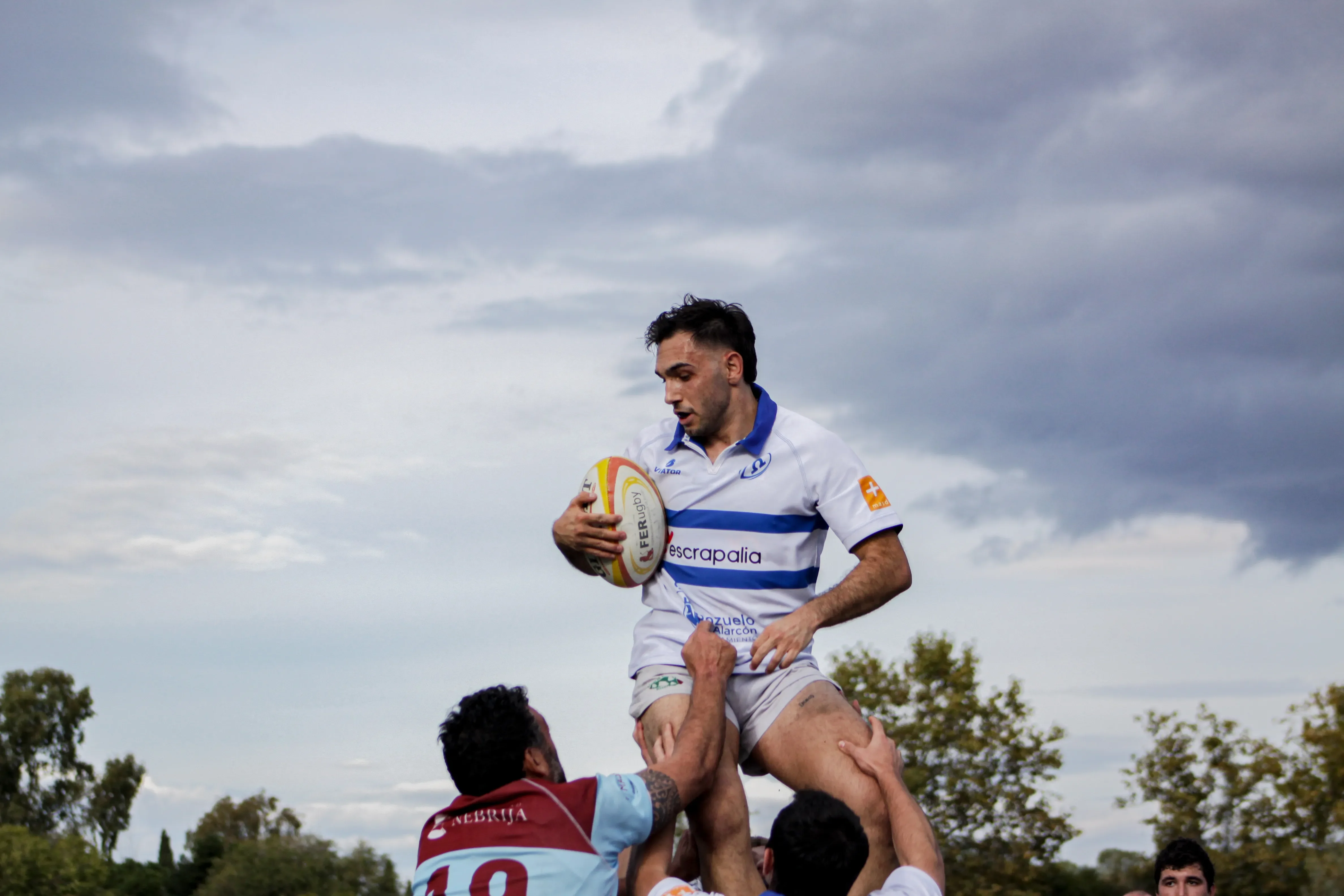 Jugador elevándose para disputar un saque de lateral durante un encuentro de rugby.