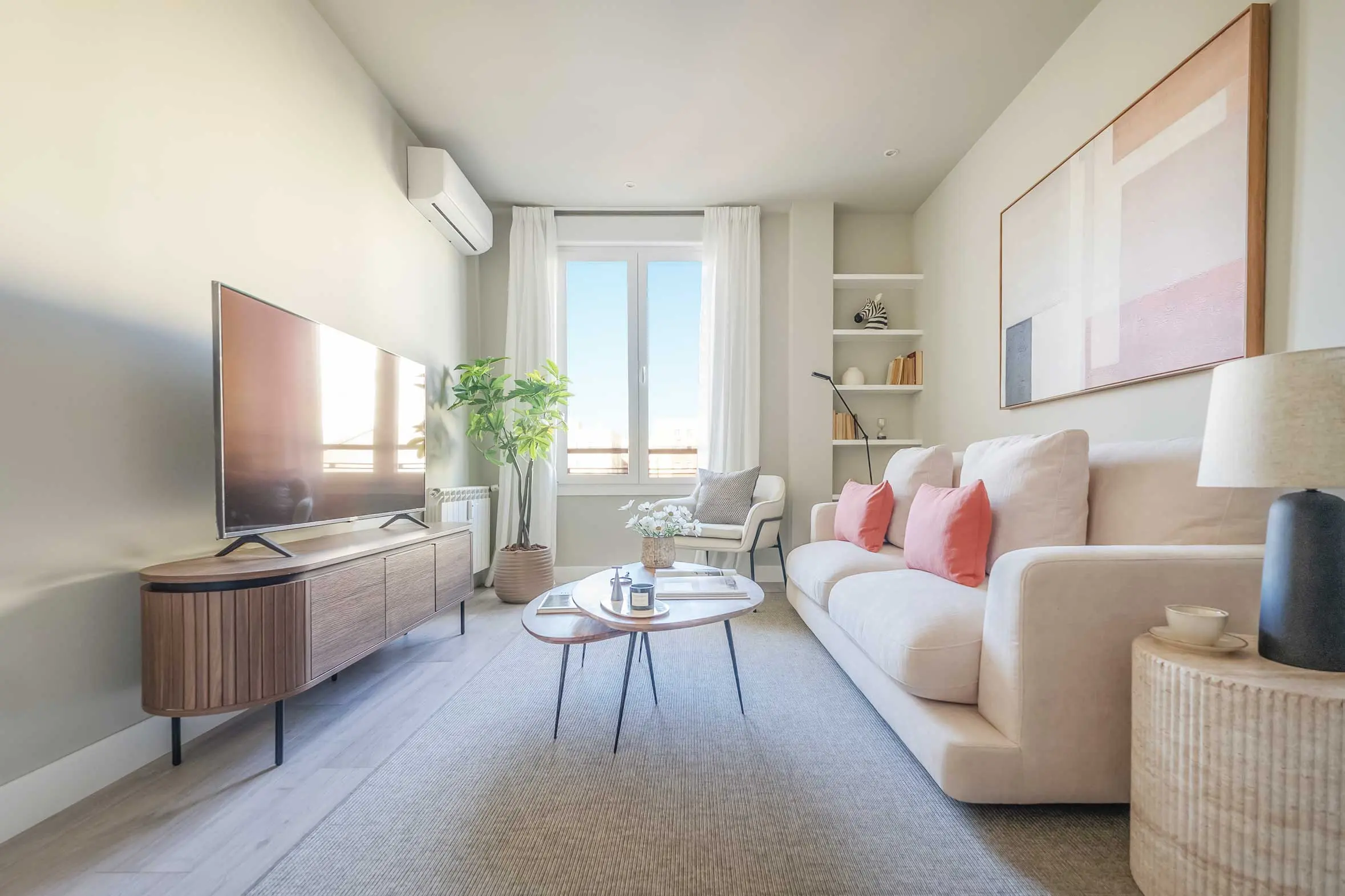 Perspectiva del mueble de televisión y rincón de lectura junto al gran ventanal del salón