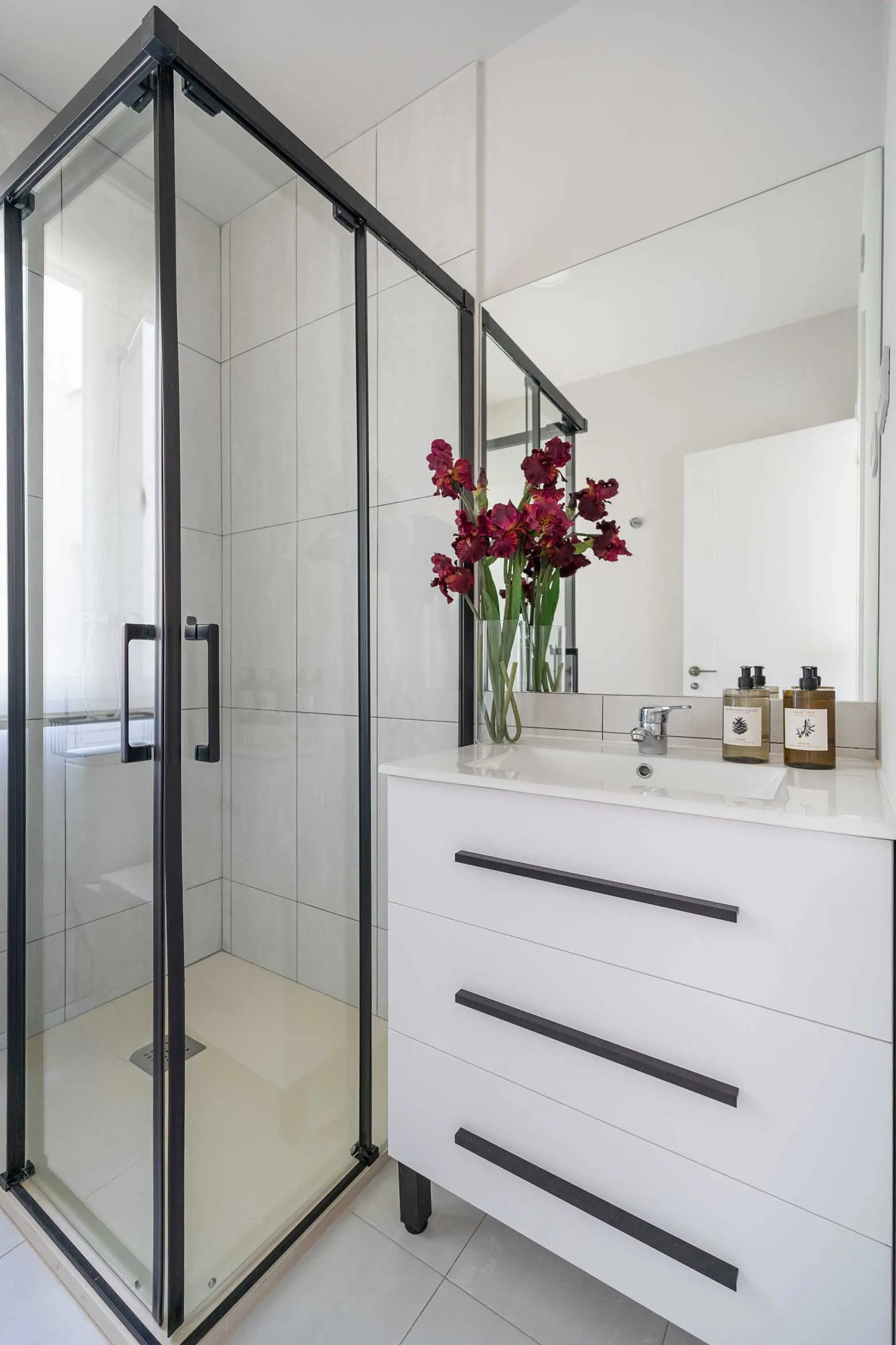 Segundo cuarto de baño con mueble blanco de líneas limpias, detalles florales y plato de ducha moderno
