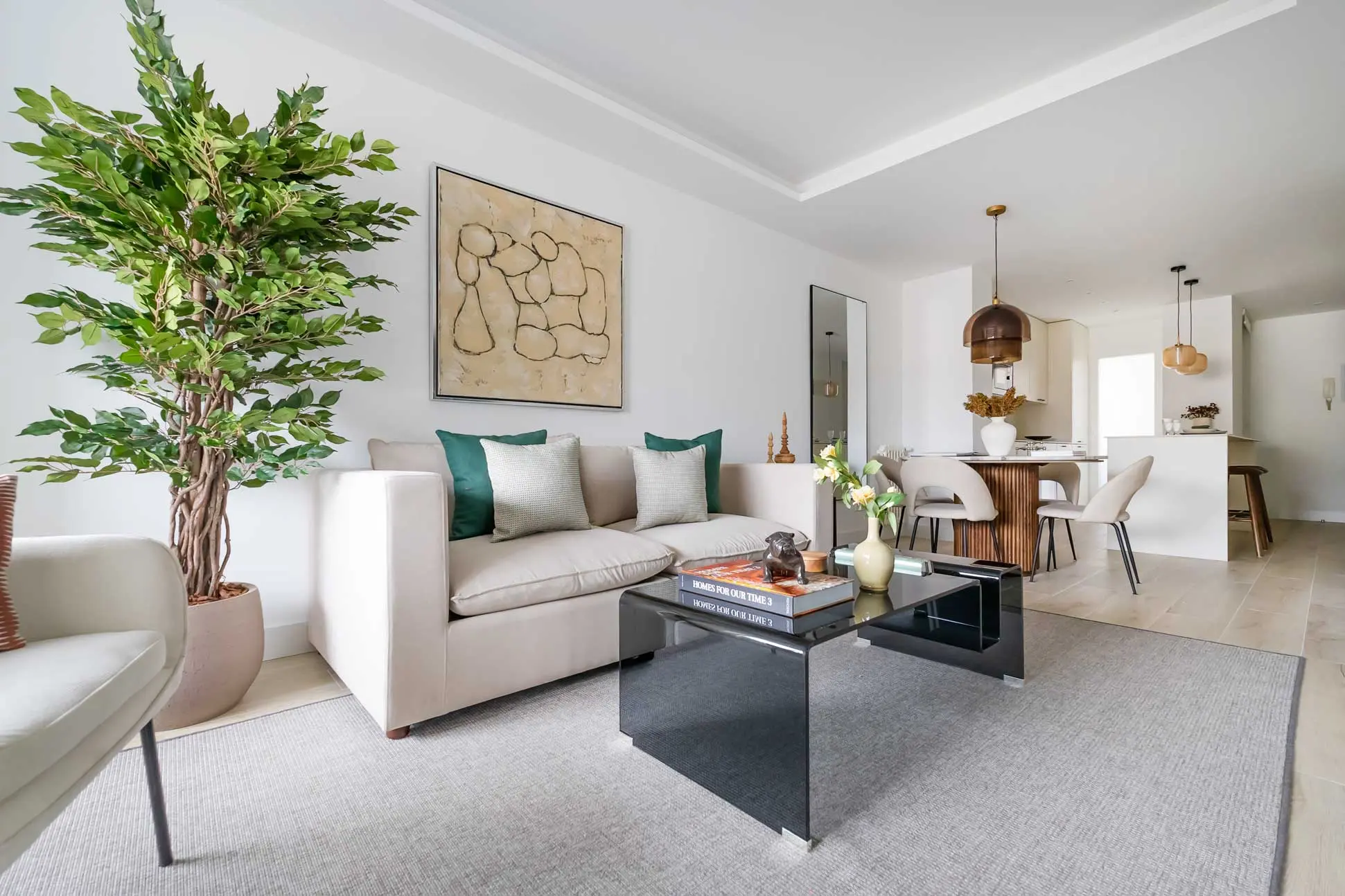 Vista del salón principal con sofá en tonos crema, mesa de centro de cristal oscuro y una gran planta de interior decorativa