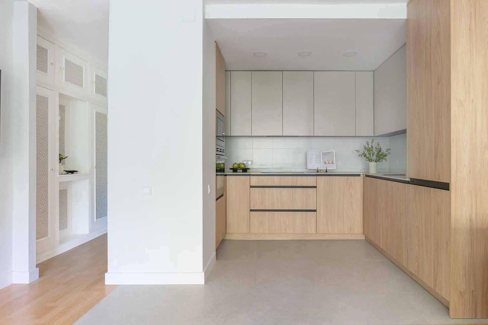 Vista cercana de la cocina contemporánea con mobiliario modular en madera y tonos beige lisos con acabados minimalistas