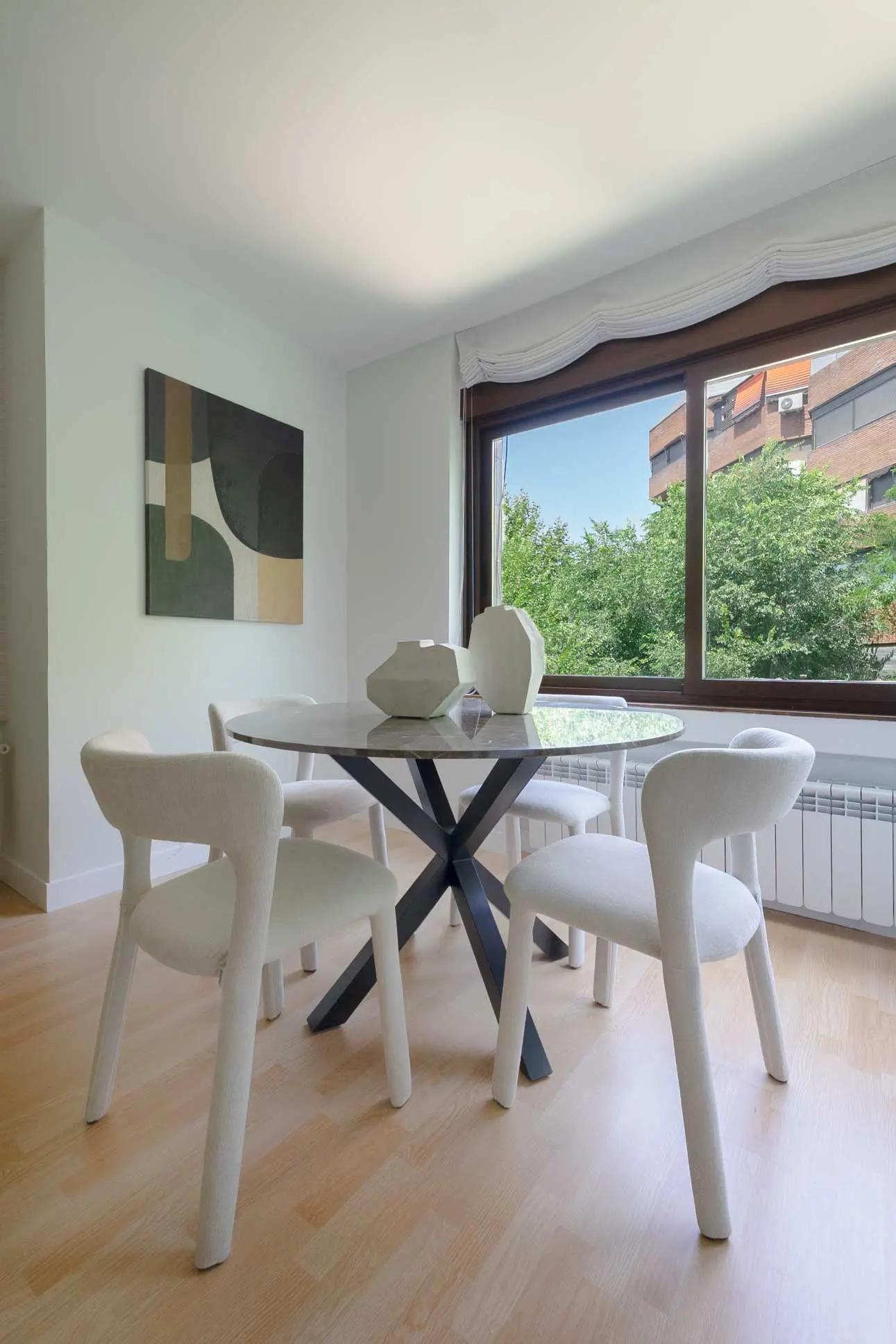 Zona de comedor con una mesa redonda de diseño, sillas tapizadas minimalistas y un ventanal que aporta claridad