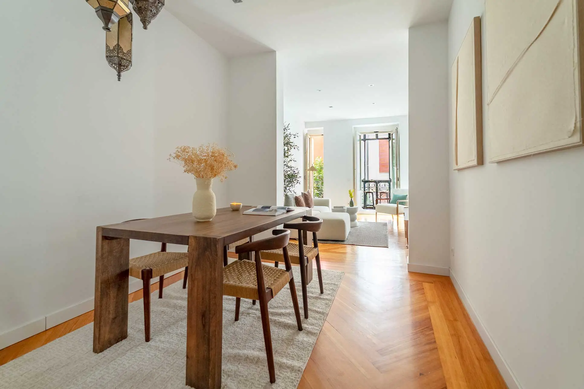 Zona de comedor con una robusta mesa de madera noble, sillas de rejilla de diseño y lámpara colgante de estilo árabe