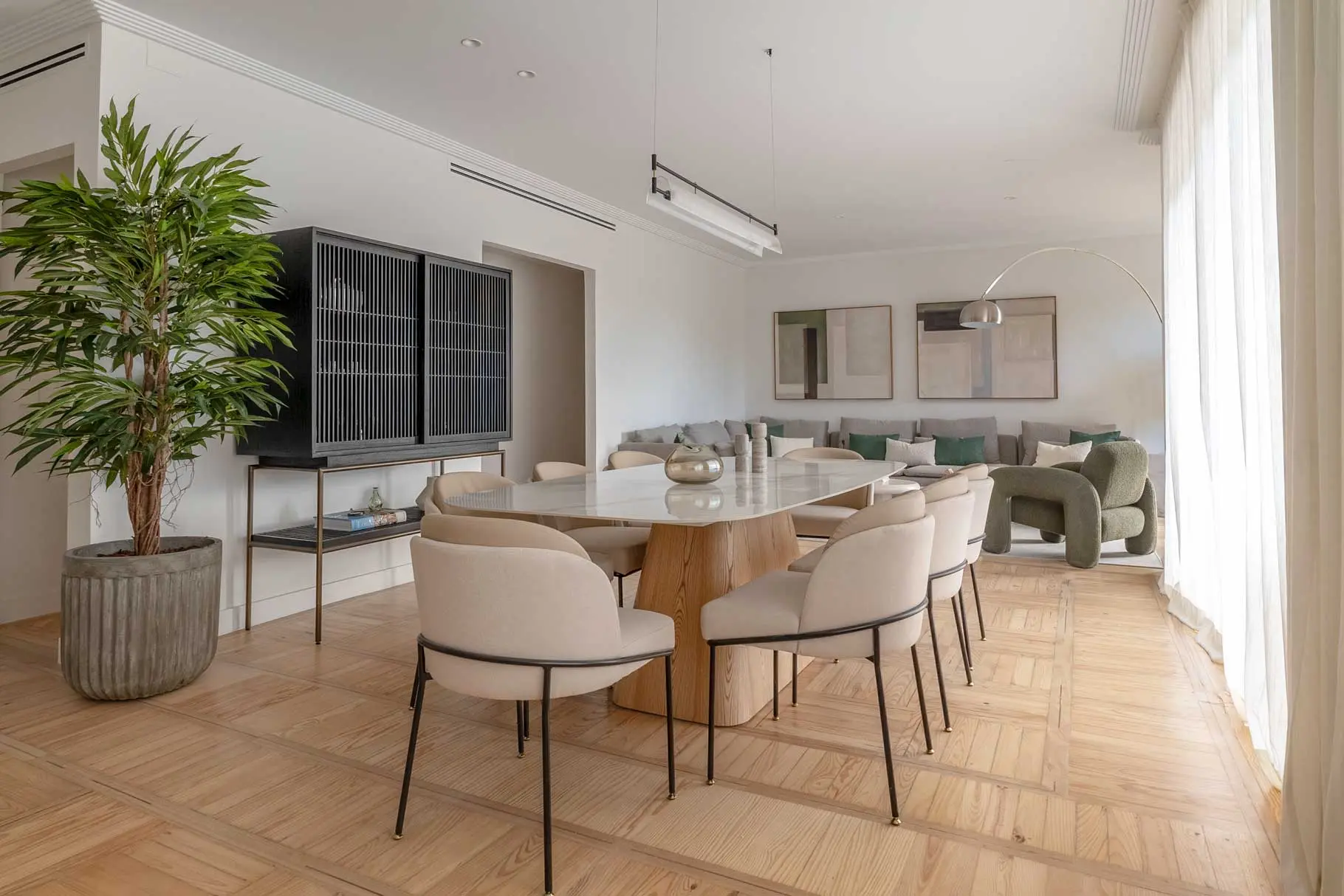 Ángulo abierto de la zona de comedor que muestra la distribución diáfana de la vivienda hacia el salón y la calidez del suelo de madera