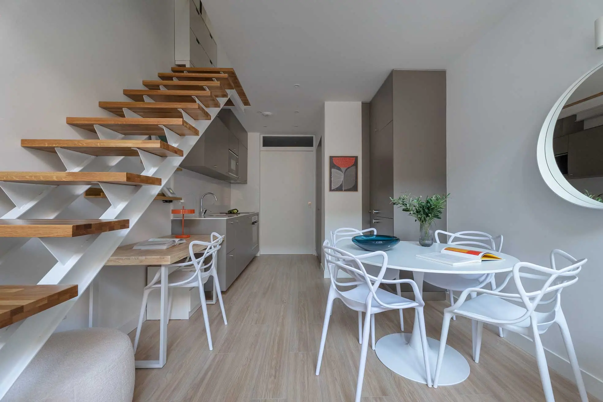 Perspectiva longitudinal del apartamento loft que muestra la integración de la cocina, la zona de comedor y la escalera de madera