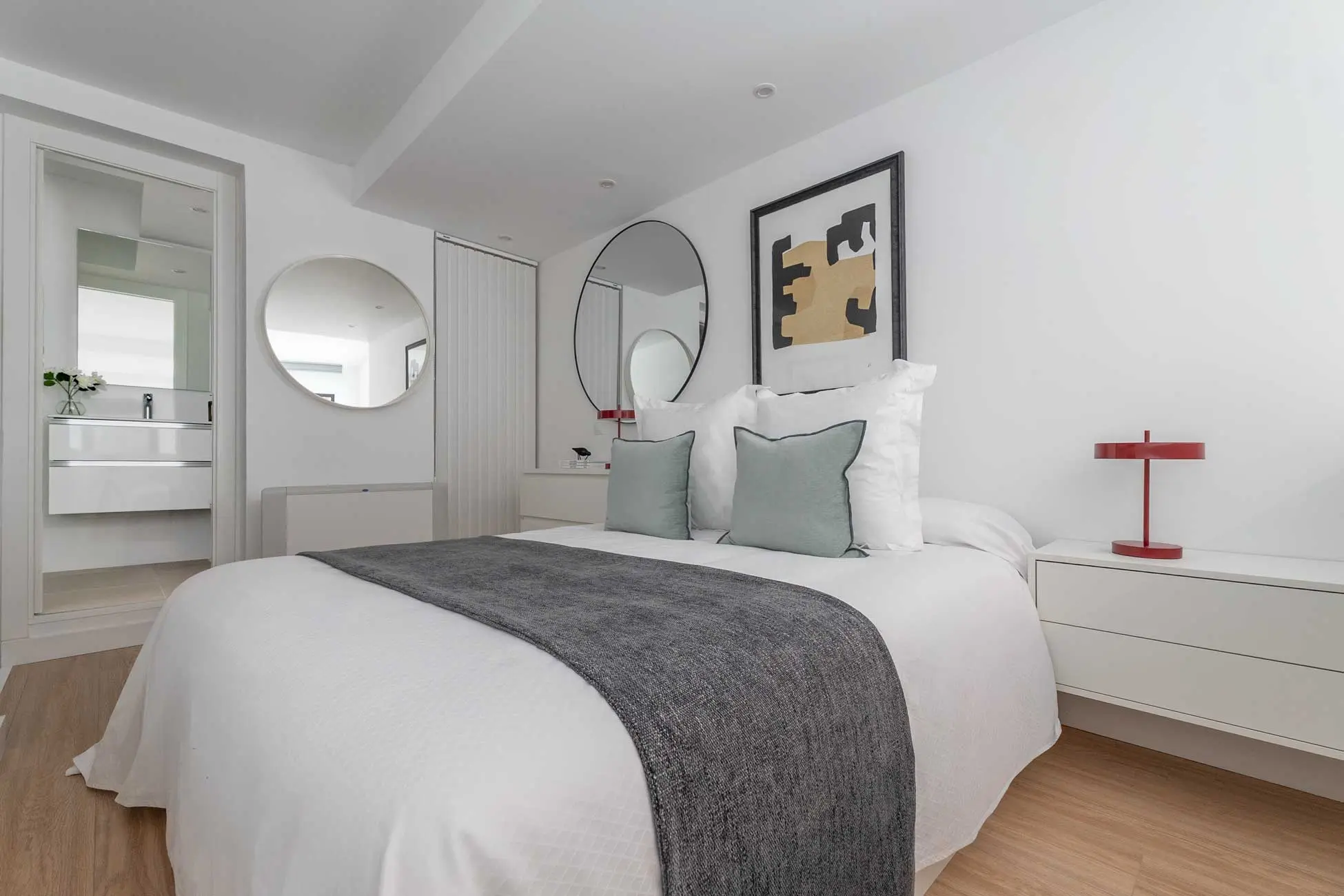 Perspectiva angular del dormitorio en planta alta que integra el cabecero, las mesillas y la vista hacia el cuarto de baño en suite
