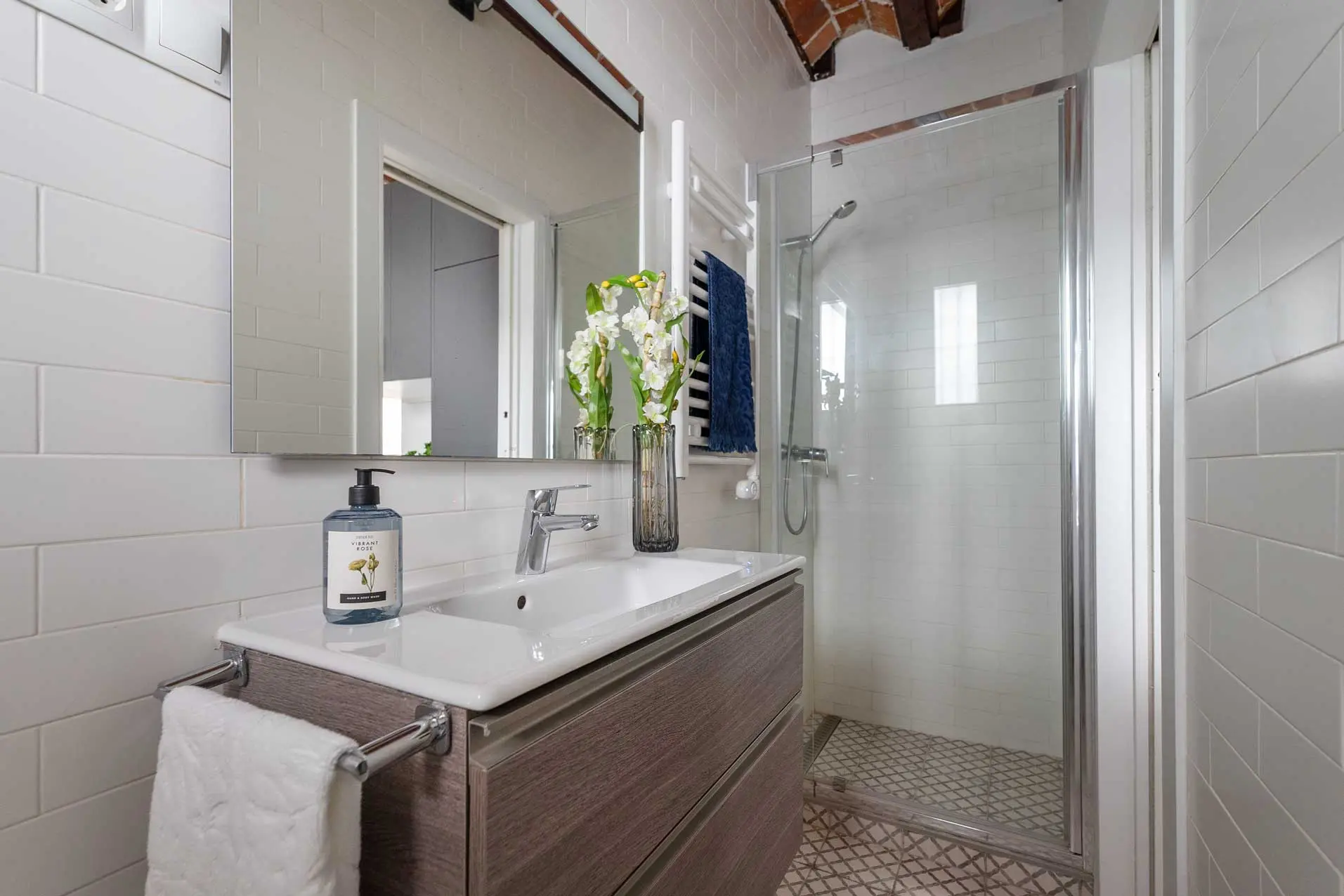 Cuarto de baño de diseño con mueble texturizado en madera, lavabo de bol cerámico blanco, azulejos tipo metro y plato de ducha