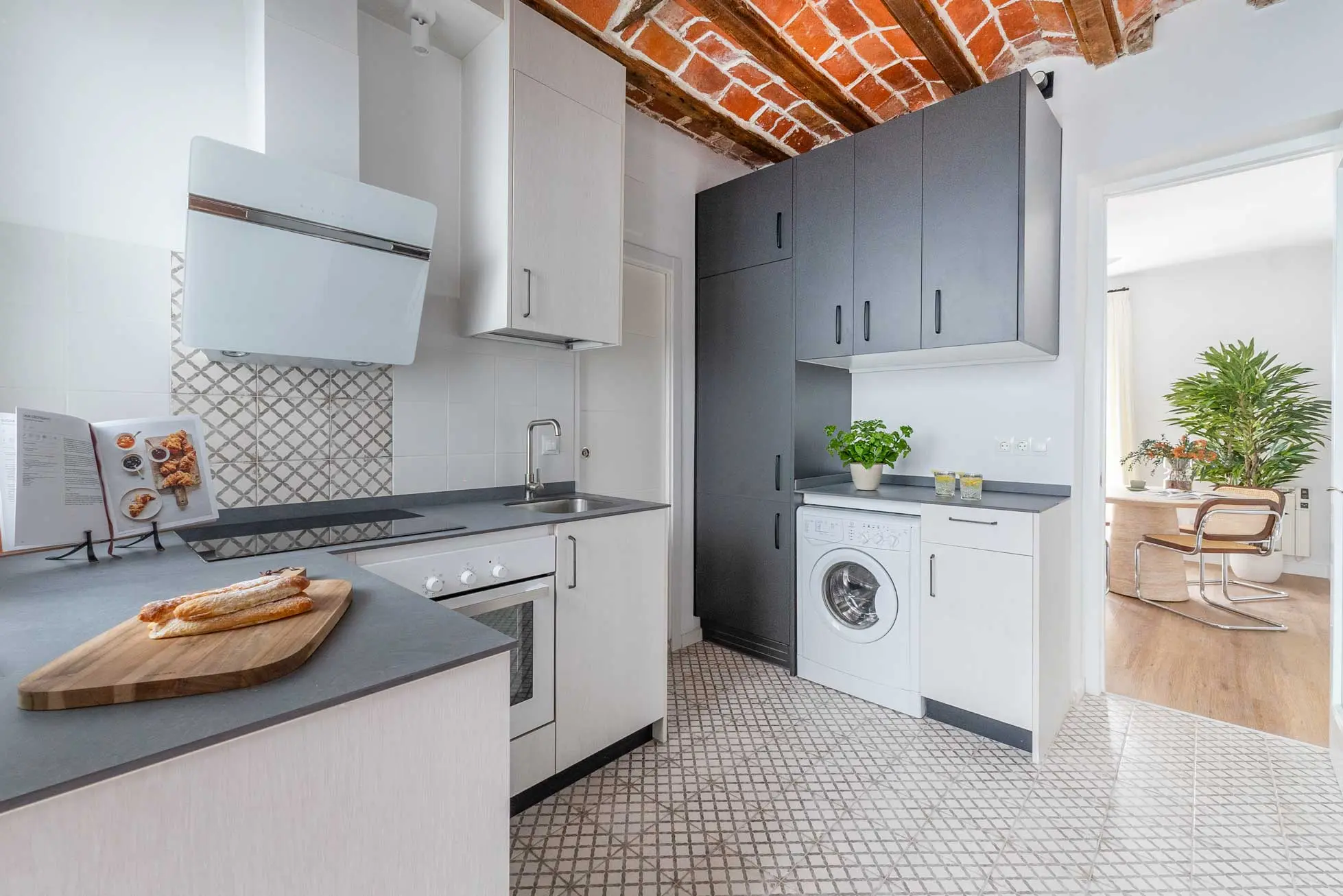 Perspectiva amplia de la cocina moderna bajo un techo antiguo recuperado de bovedilla catalana y vigas de madera vista