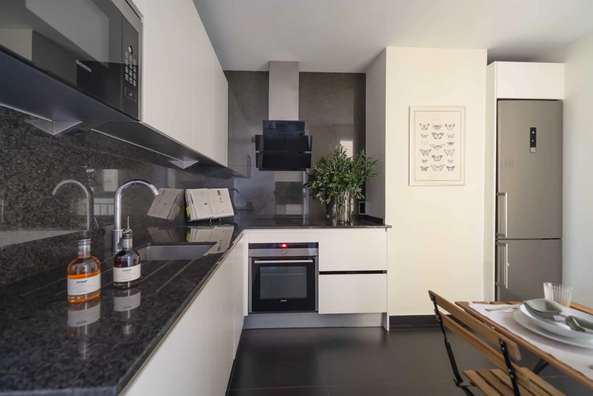 Cocina contemporánea minimalista con encimera de granito oscuro pulido, electrodomésticos integrados y zona de desayuno