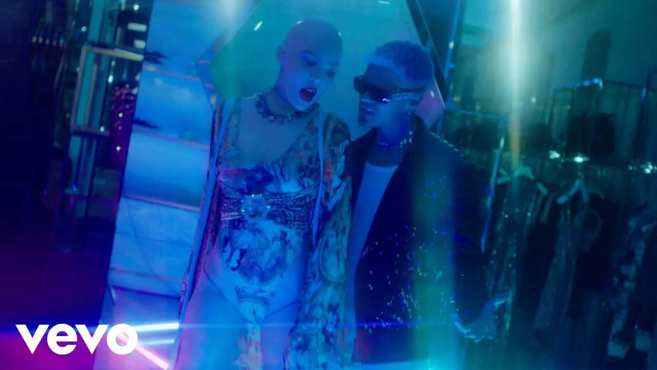 Fotograma del videoclip de Abraham Mateo y Belinda con una estética de alta costura, iluminación estilizada y reflejos en la tienda de lujo.